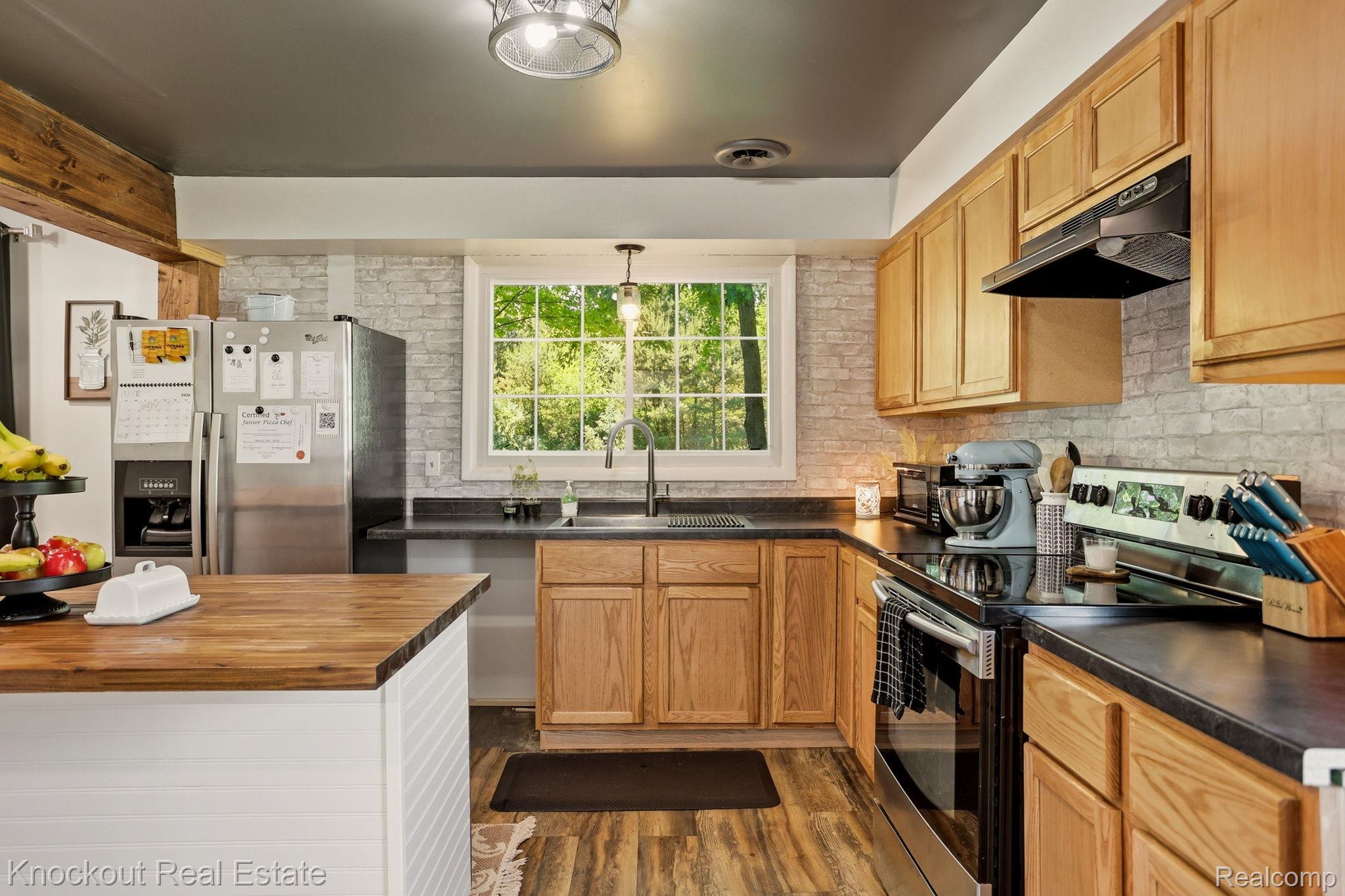 8845 Ormes Road Vassar, MI 48768 - Photo 14 of 35 Kitchen featuring wood-finish flooring, natural wood cabinetry, a built-in stainless steel oven, and a white brick-patterned backsplash