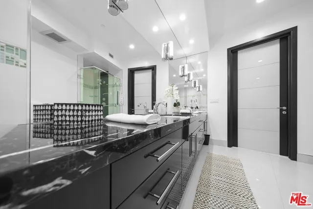 a spacious bathroom with a granite countertop sink a mirror and a shower