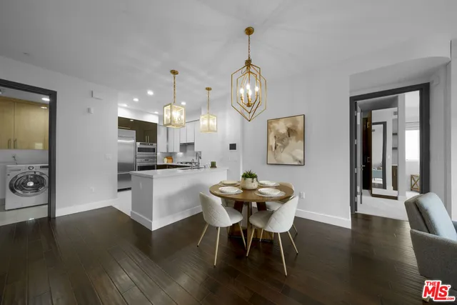 a kitchen with stainless steel appliances kitchen island granite countertop a table chairs and a wooden floor