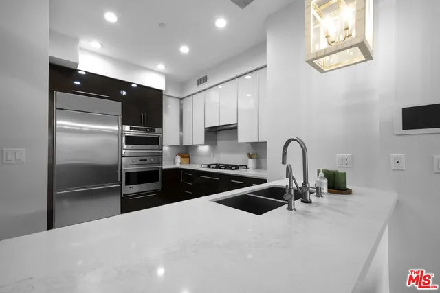a kitchen with stainless steel appliances kitchen island granite countertop a refrigerator and a sink