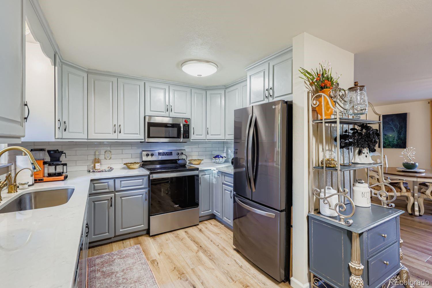 7049 Reed Court Arvada, CO 80003 - Photo 13 of 28 a kitchen with stainless steel appliances granite countertop a refrigerator stove and microwave