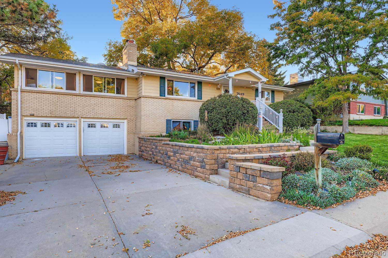 7049 Reed Court Arvada, CO 80003 - Photo 2 of 28 a view of a white house with a large windows and plants