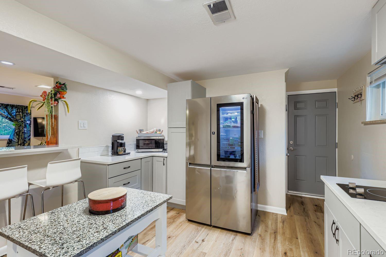 7049 Reed Court Arvada, CO 80003 - Photo 22 of 28 a kitchen with a sink and wooden floor