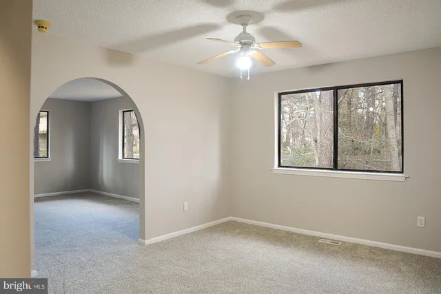 an empty room with windows and fan