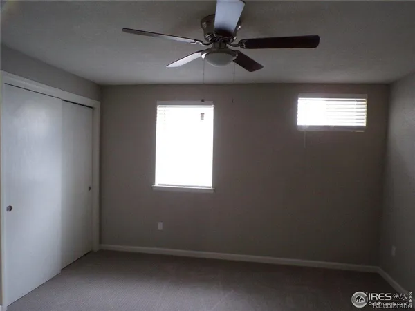 an empty room with a fan & a window