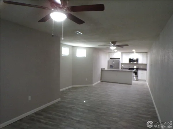 an empty room with a window and a chandelier fan