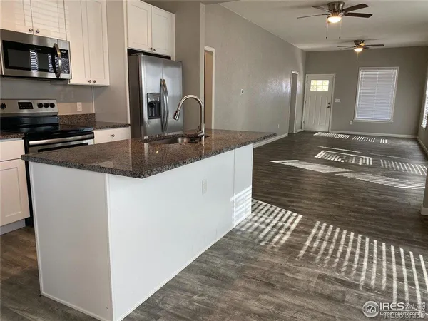 a kitchen with kitchen island granite countertop a sink appliances and cabinets