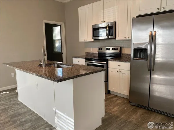 a kitchen with stainless steel appliances granite countertop a refrigerator a sink a stove a microwave and wooden floor