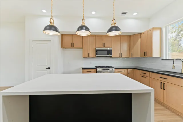 a kitchen with stainless steel appliances a sink a stove a refrigerator and white cabinets