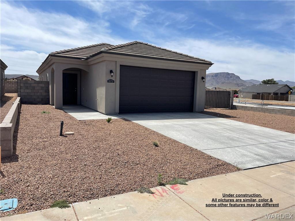 3595 North Verdugo Road Kingman, AZ 86409 - Photo 1 of 21 Contemporary stucco exterior featuring a dark garage door, a covered entry, and a concrete driveway