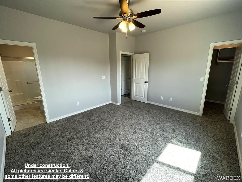 3595 North Verdugo Road Kingman, AZ 86409 - Photo 12 of 21 Spacious room featuring gray carpeting, light gray walls, a ceiling fan with integrated lighting, a white paneled door, and a walk-in closet with shelving