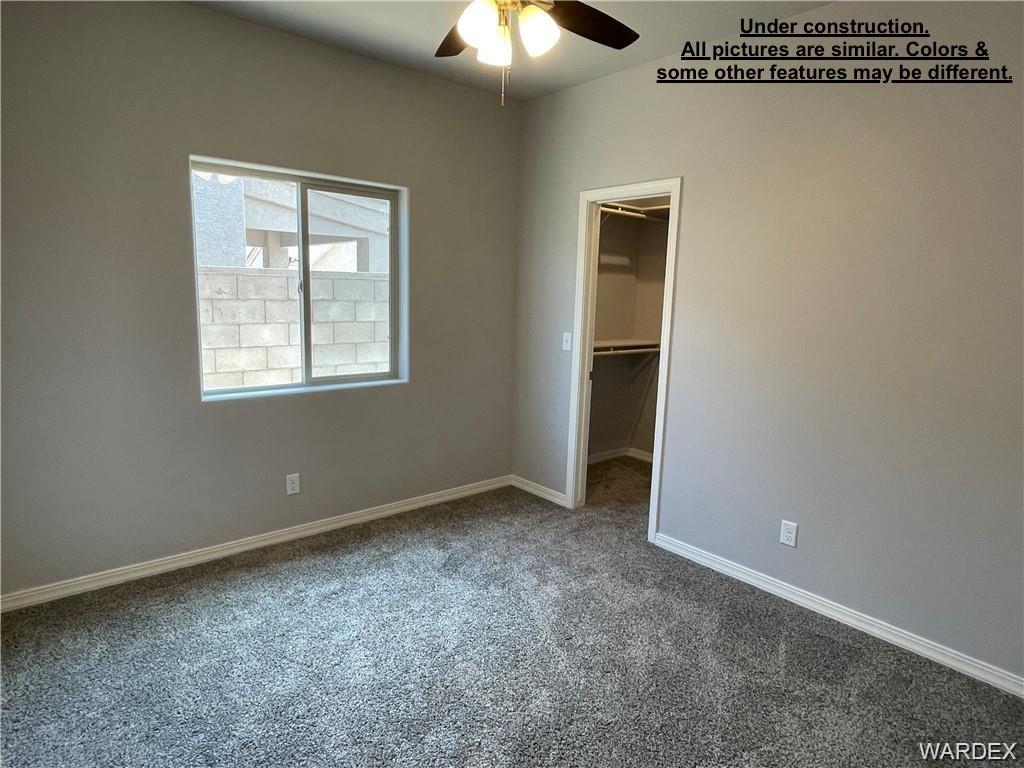 3595 North Verdugo Road Kingman, AZ 86409 - Photo 16 of 21 Bedroom featuring neutral-toned walls, gray carpeting, a ceiling fan, and a sliding window