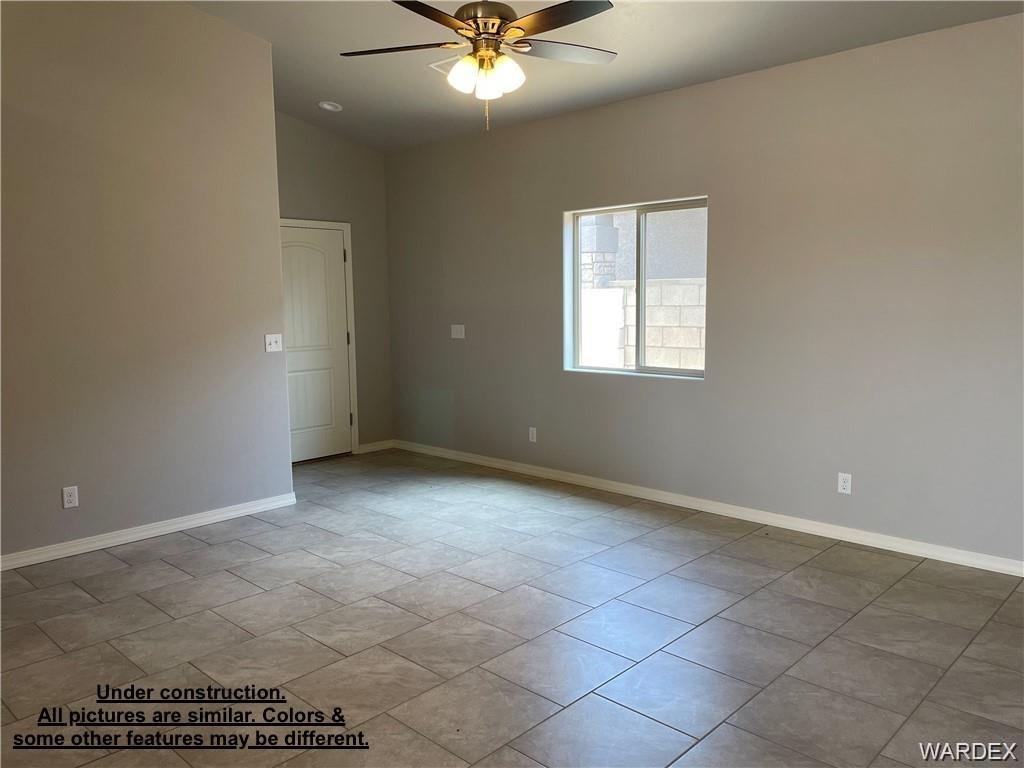 3595 North Verdugo Road Kingman, AZ 86409 - Photo 6 of 21 Spacious interior room featuring neutral wall tones, tile flooring, a window with a block wall exterior, a ceiling fan with integrated lighting, and a white paneled door