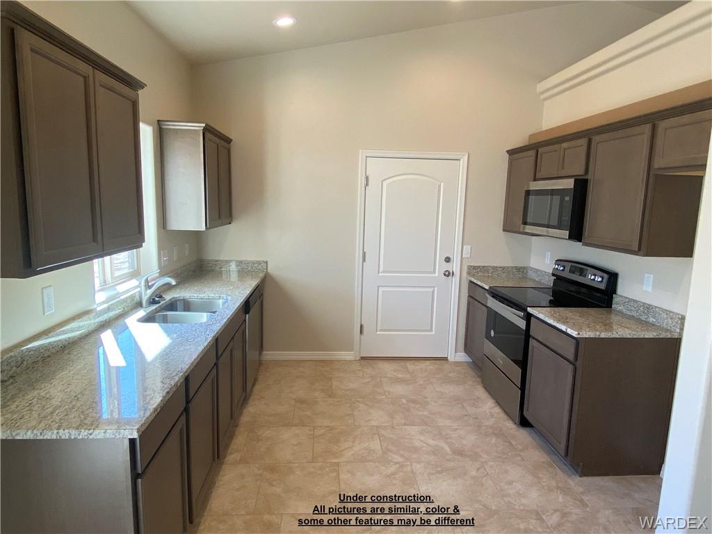 3595 North Verdugo Road Kingman, AZ 86409 - Photo 8 of 21 Modern kitchen featuring granite countertops, stainless steel appliances, dark wood-finish cabinetry, and neutral tile flooring