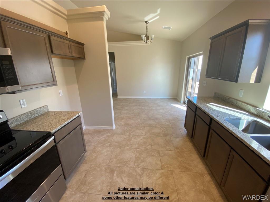 3595 North Verdugo Road Kingman, AZ 86409 - Photo 9 of 21 Kitchen and dining area featuring dark wood-finish cabinetry, light-toned countertops, and a stainless steel electric range
