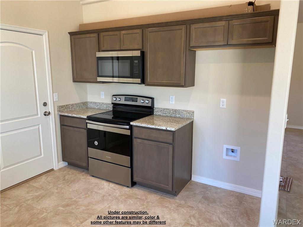 3595 North Verdugo Road Kingman, AZ 86409 - Photo 10 of 21 Kitchen featuring a stainless steel range and microwave, light-toned cabinetry, granite-look countertops, and tile flooring