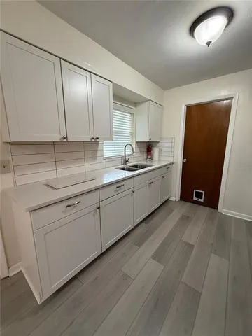a kitchen with a sink cabinets and wooden floor