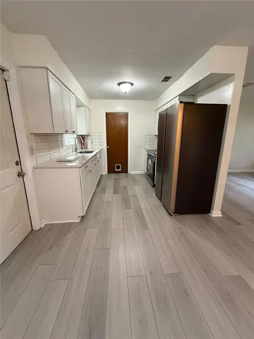 a view of a kitchen with wooden floor and electronic appliances
