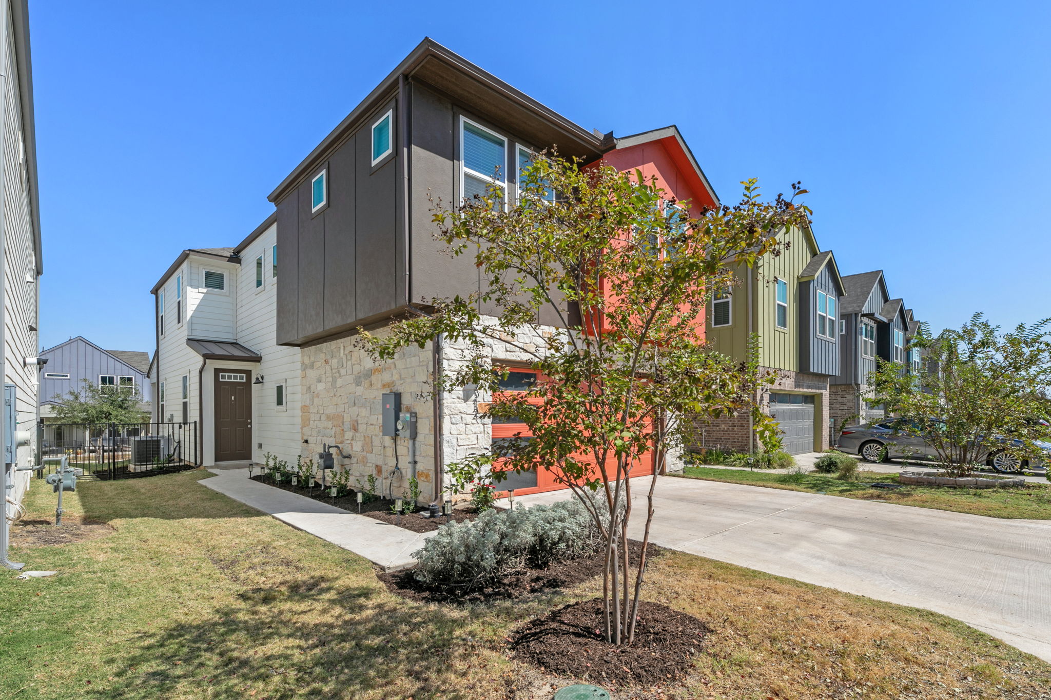 7312 Travertine Spring Drive Austin, TX 78744 - Photo 3 of 32 Modern townhomes feature varied siding and attached garages, offering contemporary suburban living.