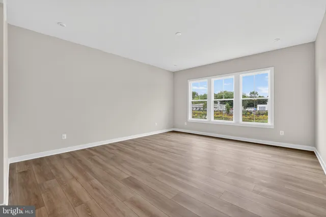 a view of an empty room with wooden floor and windows