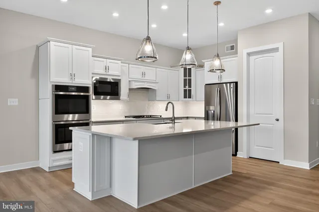 a kitchen with stainless steel appliances granite countertop a refrigerator a stove a sink and white cabinets