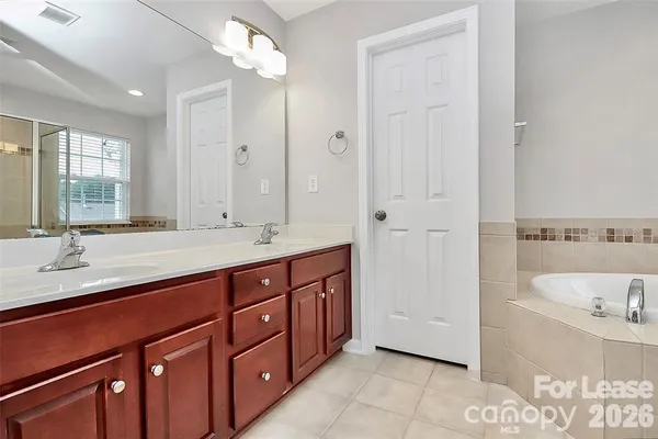 a spacious bathroom with a tub double sink and mirror