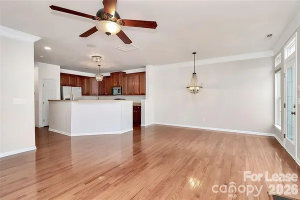 a view of a kitchen with a sink a refrigerator a ceiling fan and wooden floor