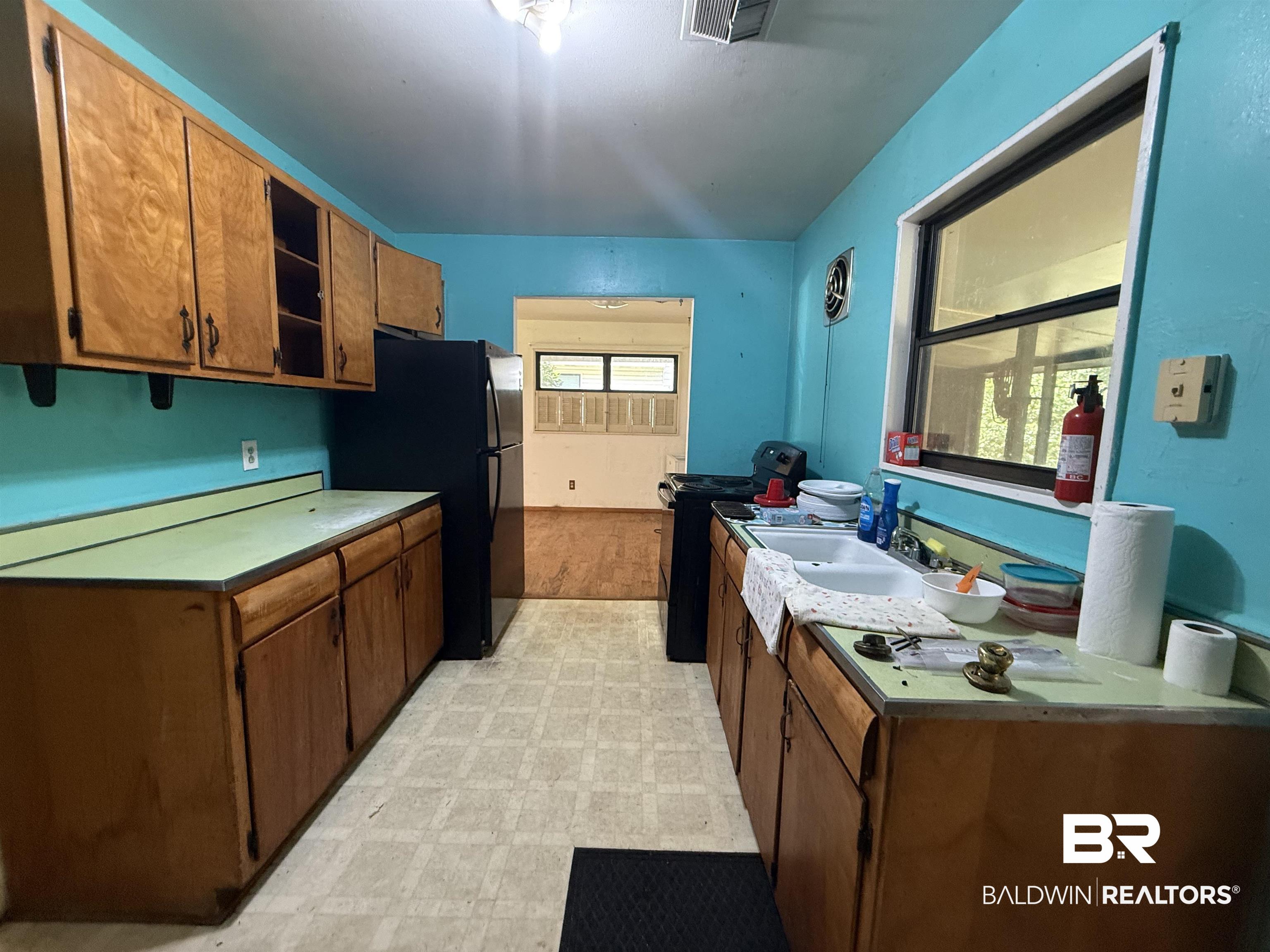 711 Wilshire Road Mobile, AL 36609 - Photo 5 of 11 Galley kitchen featuring wood-finish cabinetry, a double basin sink, and a large window