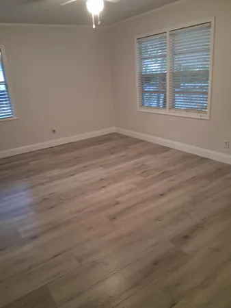 an empty room with wooden floor and windows