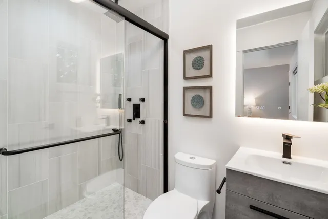 a bathroom with a sink a toilet a mirror and shower