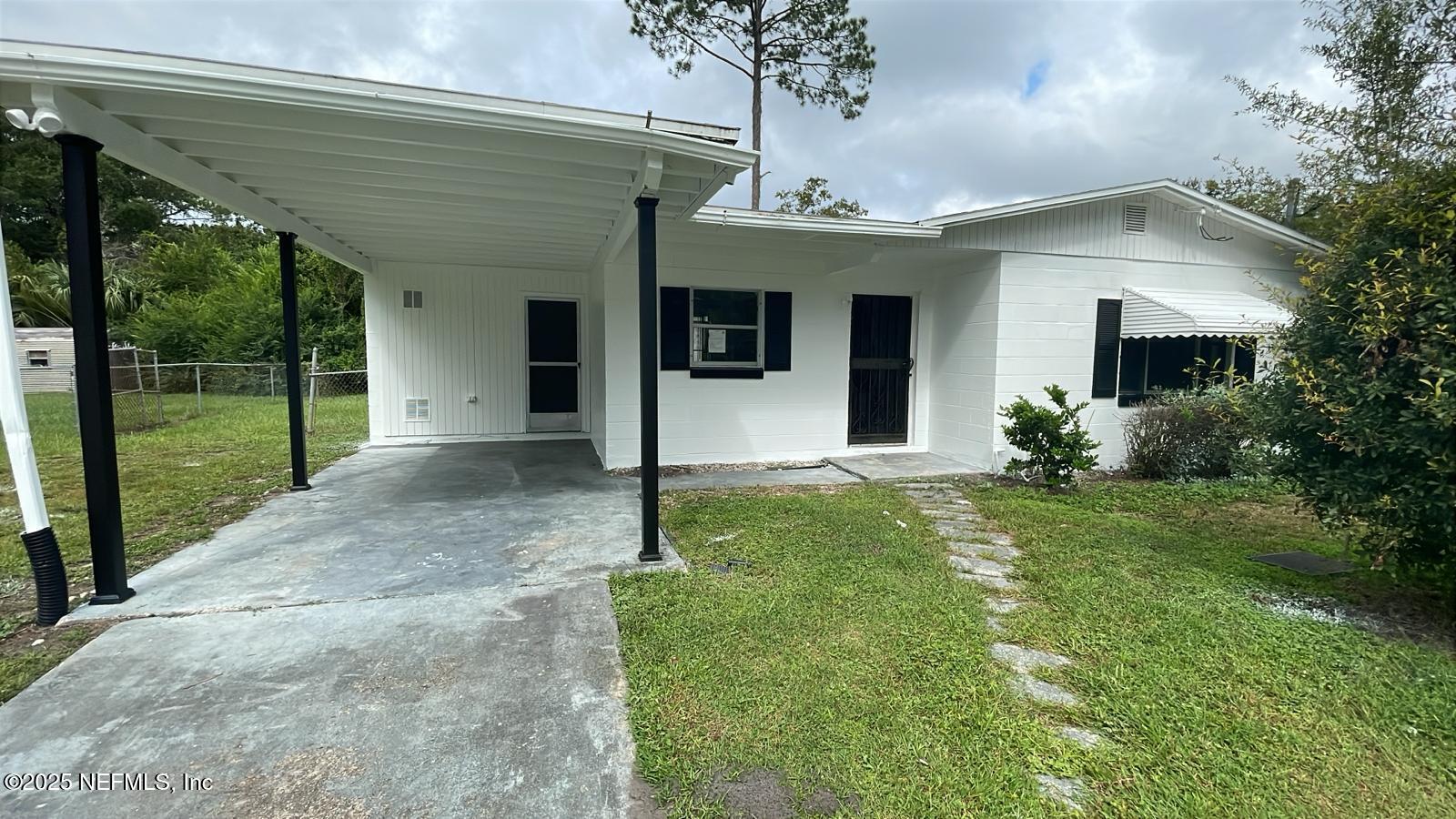 a view of a house with a small yard and a large tree