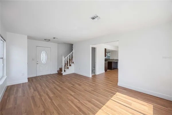 a view of an empty room with window and wooden floor