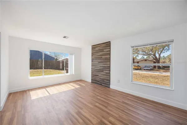 an empty room with wooden floor and windows