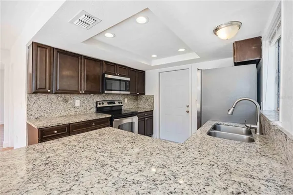 a kitchen with stainless steel appliances granite countertop a sink stove and refrigerator