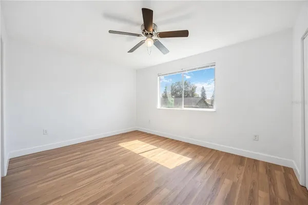 a view of empty room with wooden floor and fan