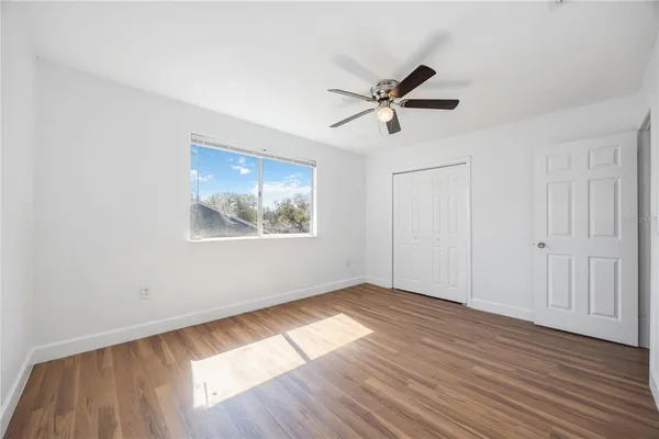 a view of empty room with wooden floor and fan