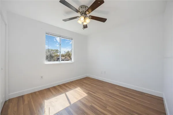 an empty room with a window and a fan