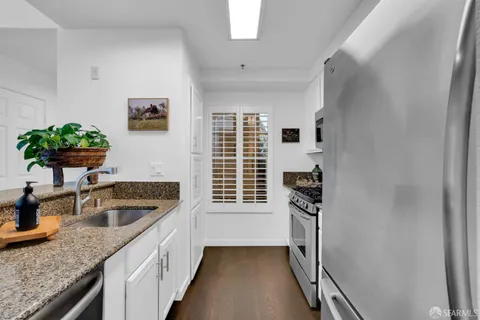 a kitchen with dining table chairs wooden floor and a refrigerator