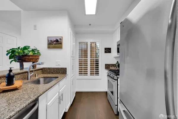 a kitchen with dining table chairs wooden floor and a refrigerator