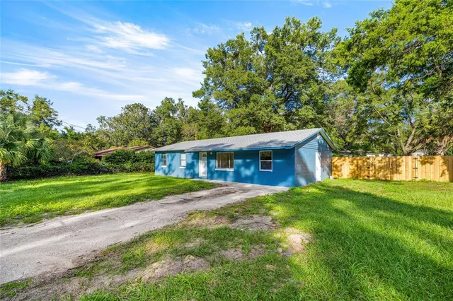 a view of a yard in front of a house with large trees