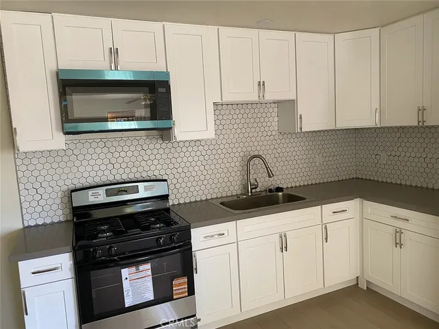 a kitchen with white cabinets and black appliances