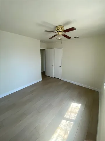 an empty room with windows and fan