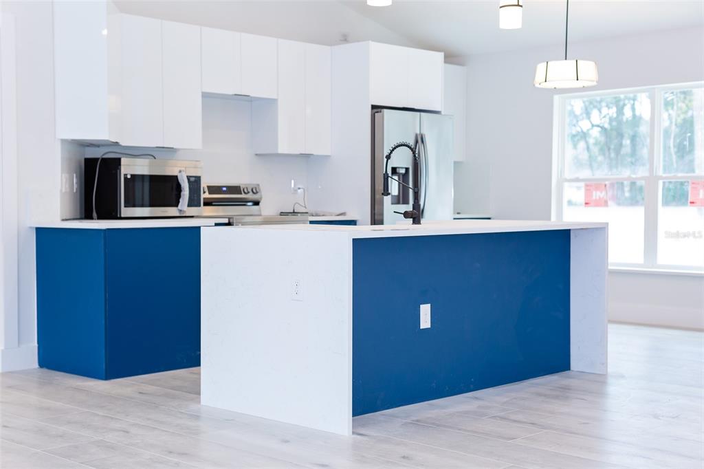 16645 Southwest 59th Court Road Ocala, FL 34473 - Photo 9 of 16 a kitchen with stainless steel appliances granite countertop a refrigerator a sink dishwasher a stove and white countertops with wooden floor
