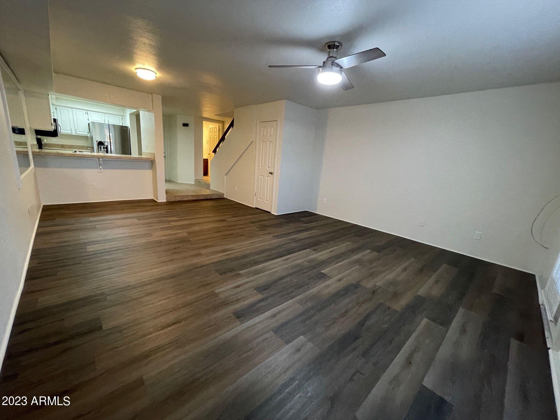 2121 West Union Hills Drive, Unit 108 Phoenix, AZ 85027 - Photo 10 of 35 an empty room with wooden floor kitchen view and a ceiling fan