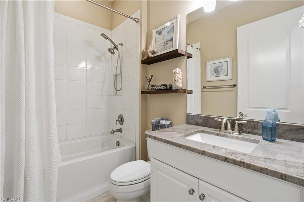 8665 Dilillo Court Naples, FL 34119 - Photo 18 of 42 a bathroom with a granite countertop sink a toilet and shower