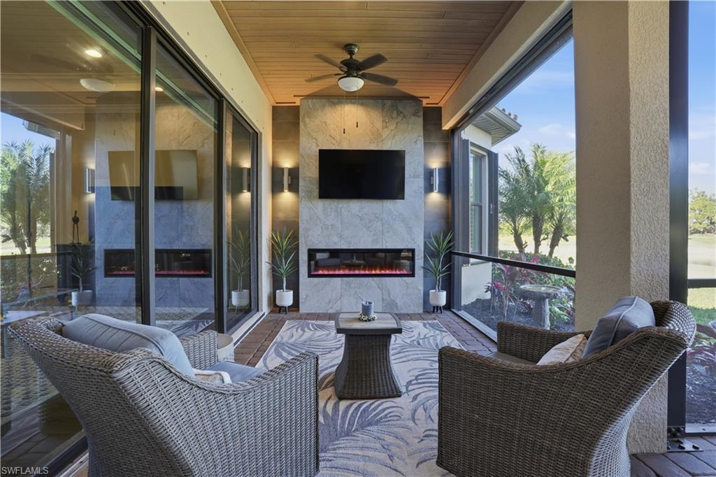 8665 Dilillo Court Naples, FL 34119 - Photo 22 of 42 a living room with furniture a fireplace and a flat screen tv