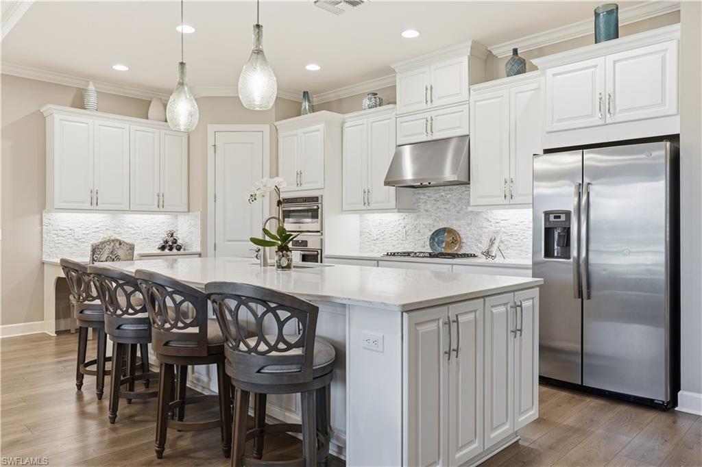 8665 Dilillo Court Naples, FL 34119 - Photo 7 of 42 a kitchen with granite countertop a table chairs microwave a sink and refrigerator
