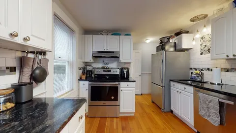 a kitchen with stainless steel appliances a stove a sink dishwasher a refrigerator and a stove with wooden floor