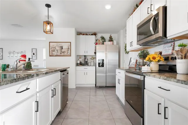 a kitchen with stainless steel appliances granite countertop a refrigerator a sink dishwasher and white cabinets with wooden floor