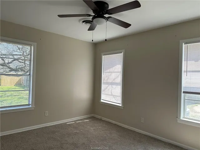 an empty room with a window and a fan